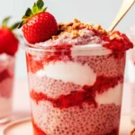 Strawberry chia pudding layered with cream in a clear glass jar
