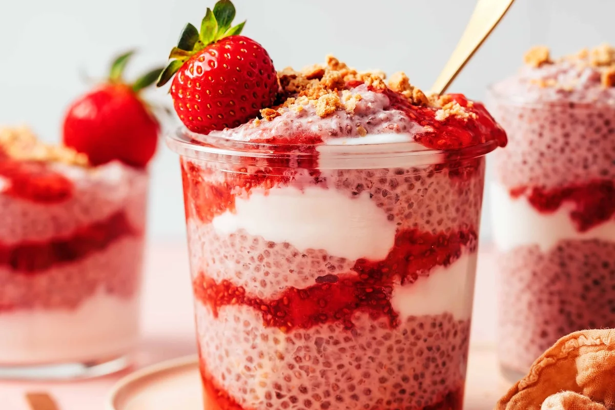 Strawberry chia pudding layered with cream in a clear glass jar