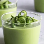 Glass of creamy green avocado gazpacho garnished with cucumber ribbons