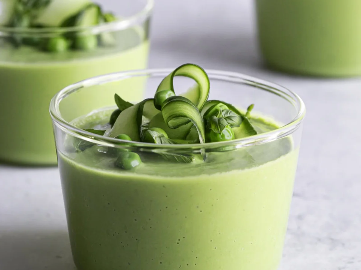 Glass of creamy green avocado gazpacho garnished with cucumber ribbons