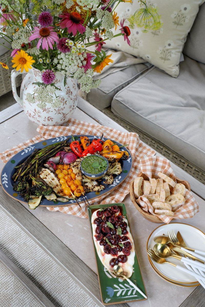 Outdoor table set with grilled vegetable platter and wildflowers