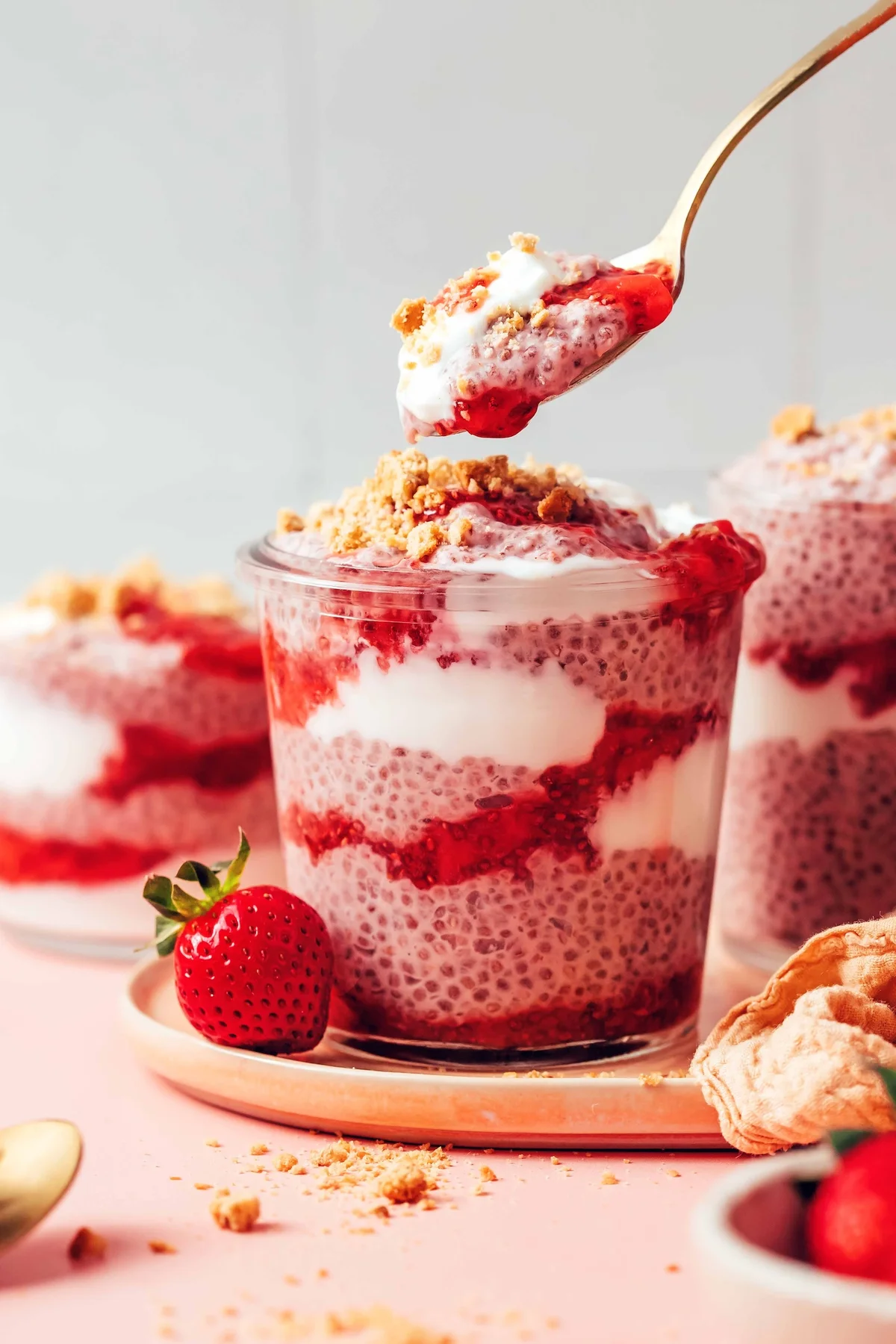 Layered strawberry chia pudding jar with a lifted spoonful