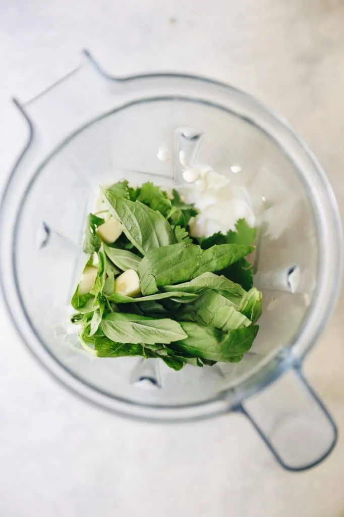 Fresh herbs and garlic being blended into yogurt dressing