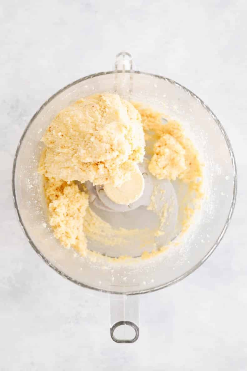 Food processor bowl with crumbly almond flour pastry dough