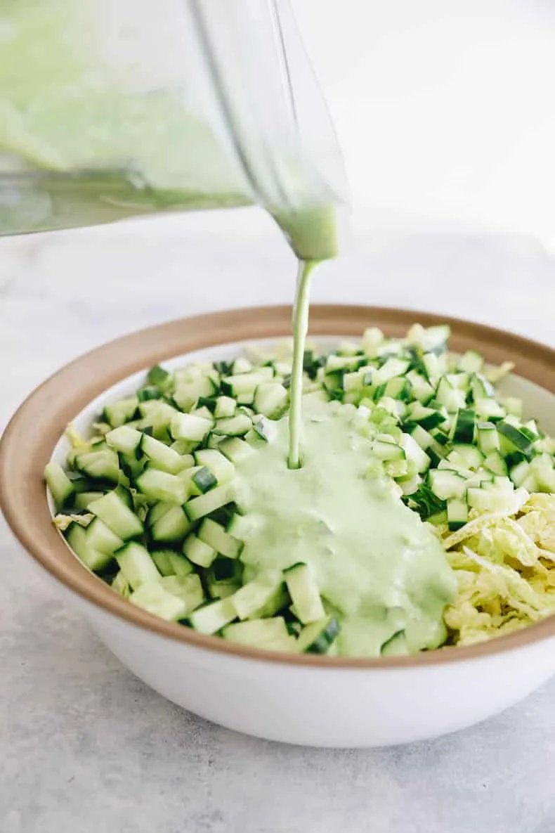 Green goddess dressing being poured over the salad bowl