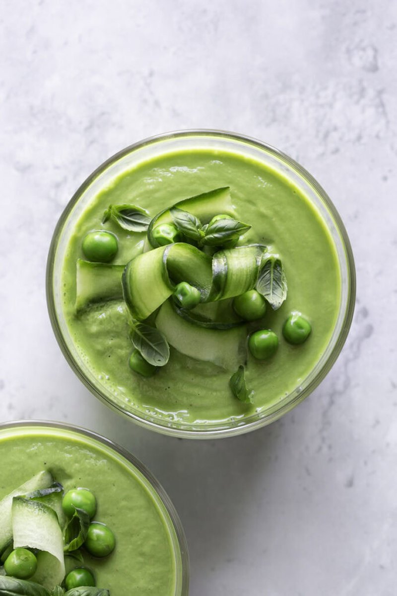 Bowls of green gazpacho topped with cucumber rosette and peas