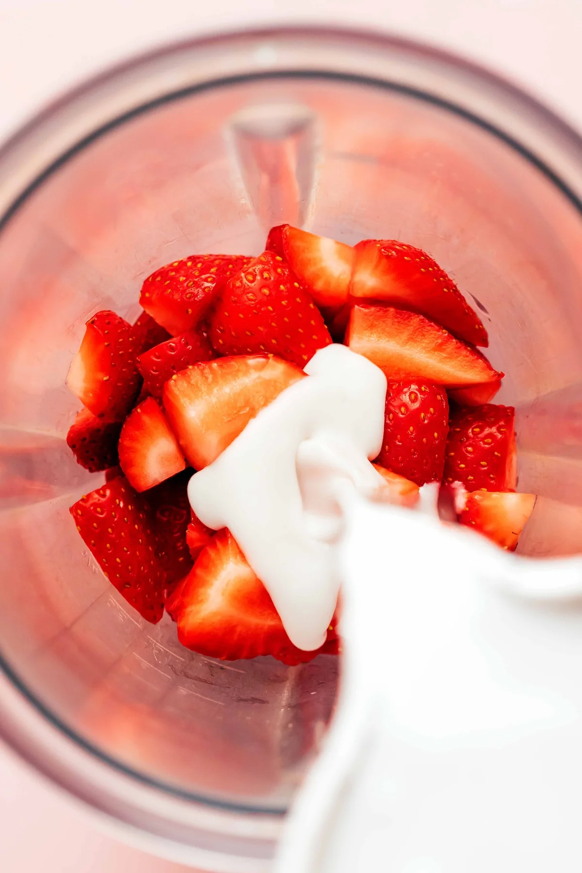 Strawberries and coconut milk being blended together