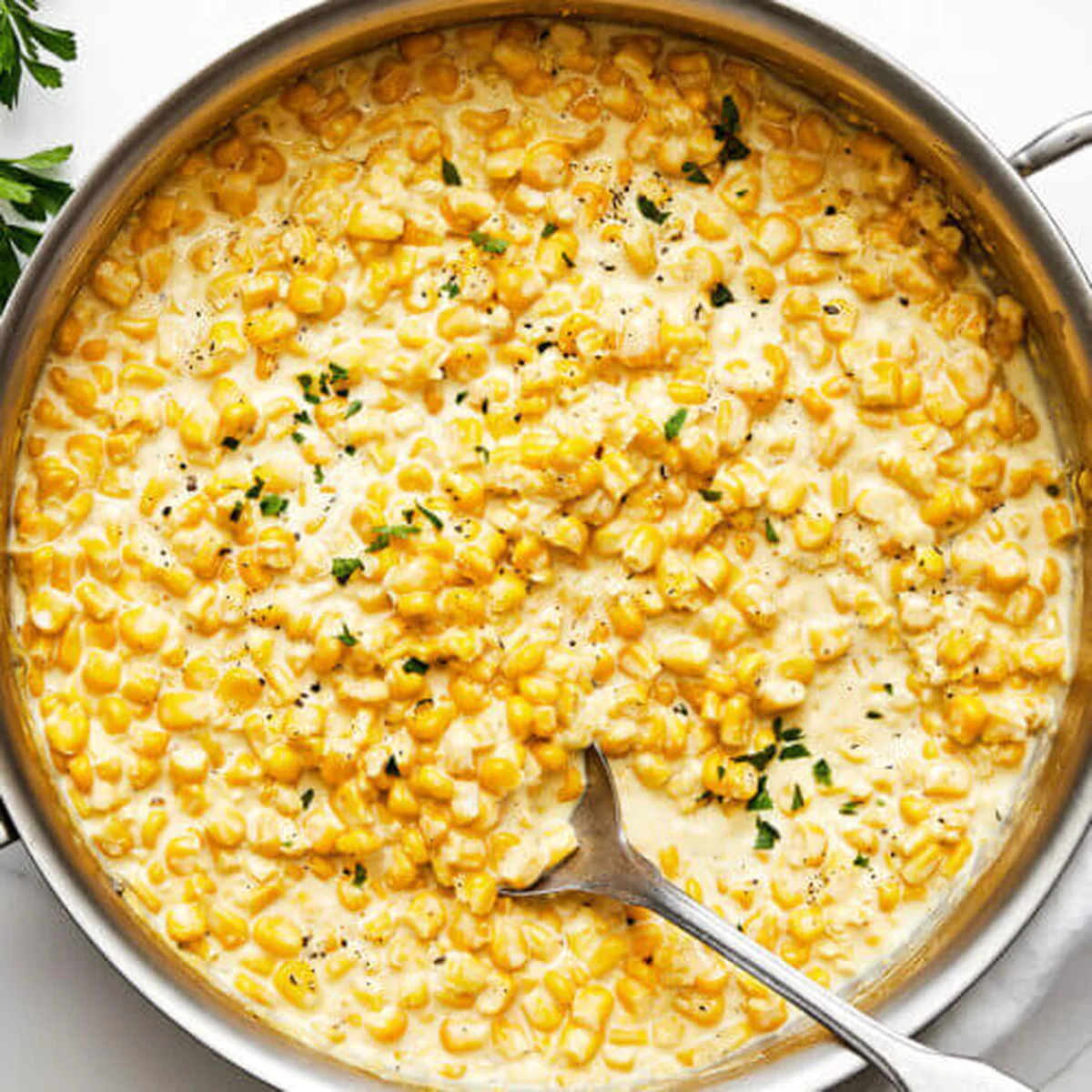 Creamed corn glistening in stainless steel kitchen skillet