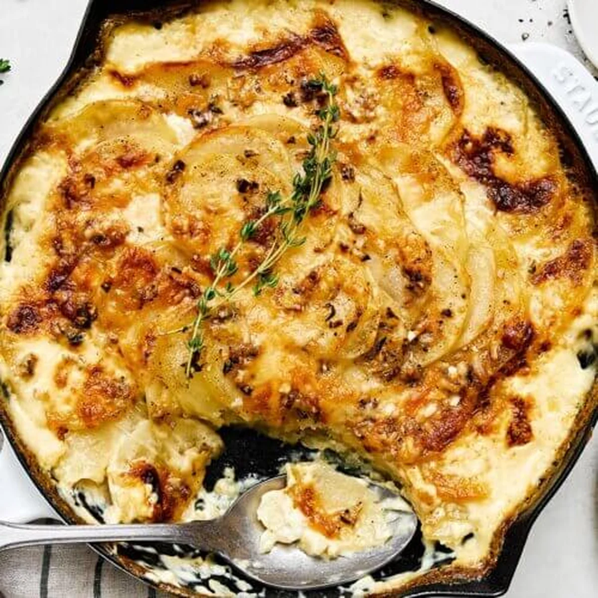 Scalloped potatoes with golden bubbly top in cast iron pan
