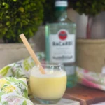 Frozen piña colada with frothy top and yellow paper straw