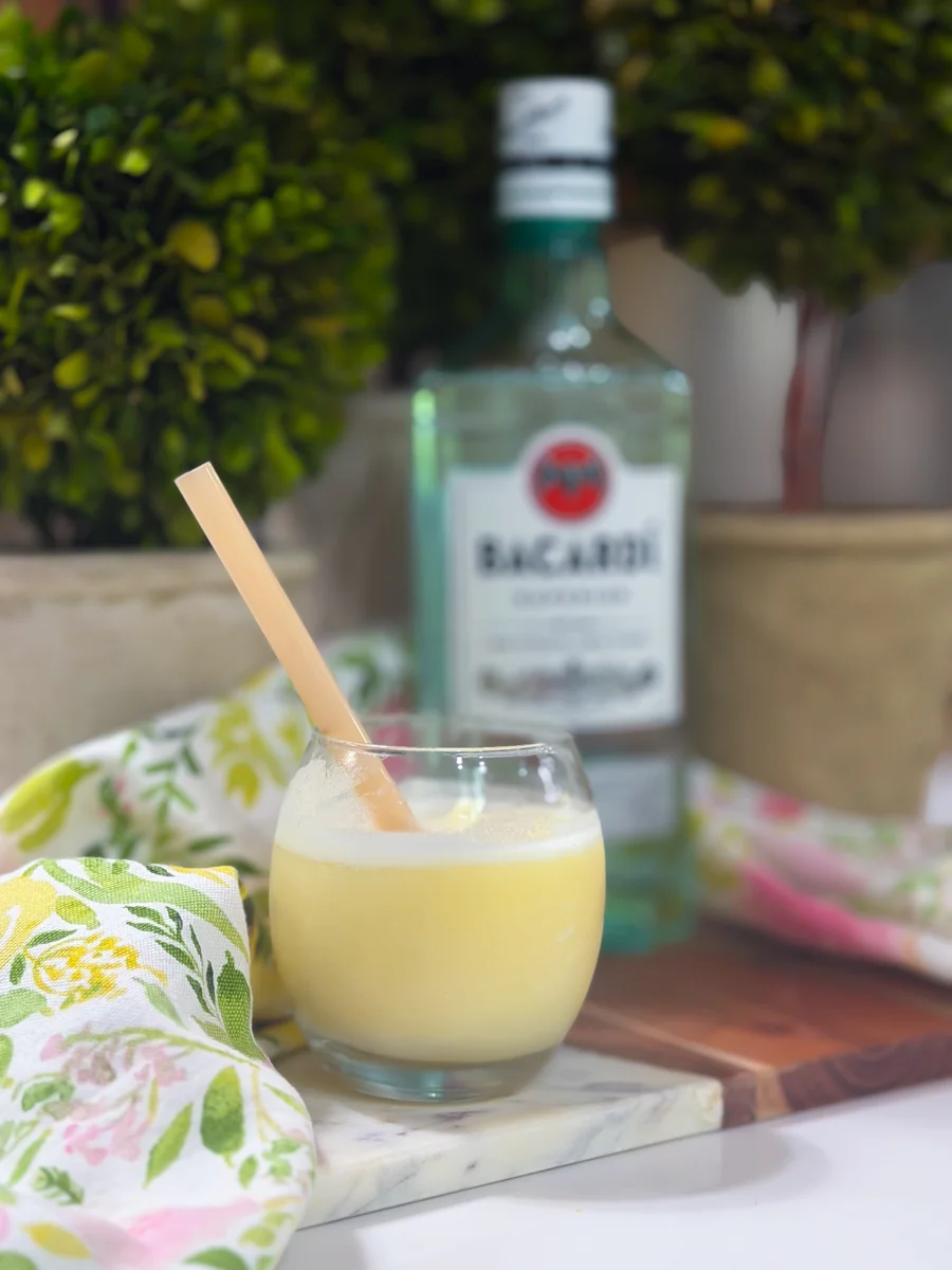 Frozen piña colada with frothy top and yellow paper straw