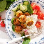 Baked Greek chicken meatballs over rice with tzatziki and fresh vegetables