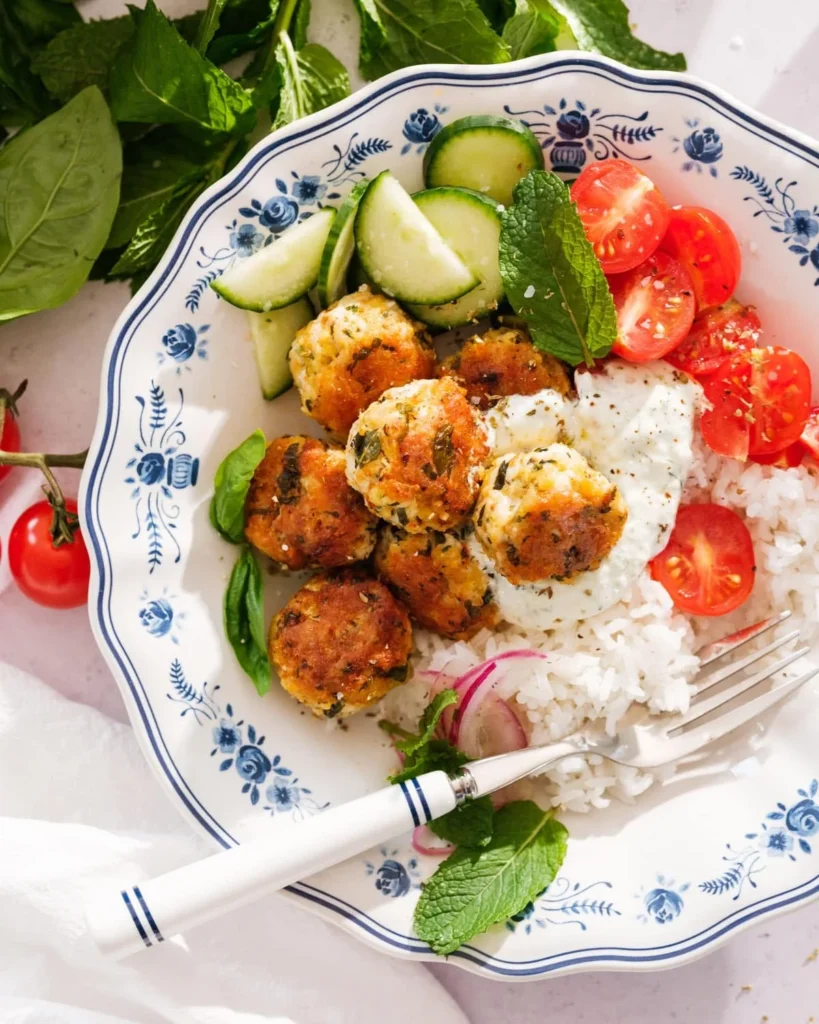 Baked Greek chicken meatballs over rice with tzatziki and fresh vegetables