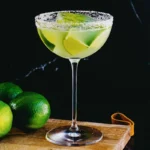 Texas margarita in a salt-rimmed coupe glass with lime wedges