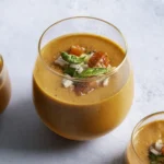 Bowl of bright red cherry tomato gazpacho garnished with fresh basil