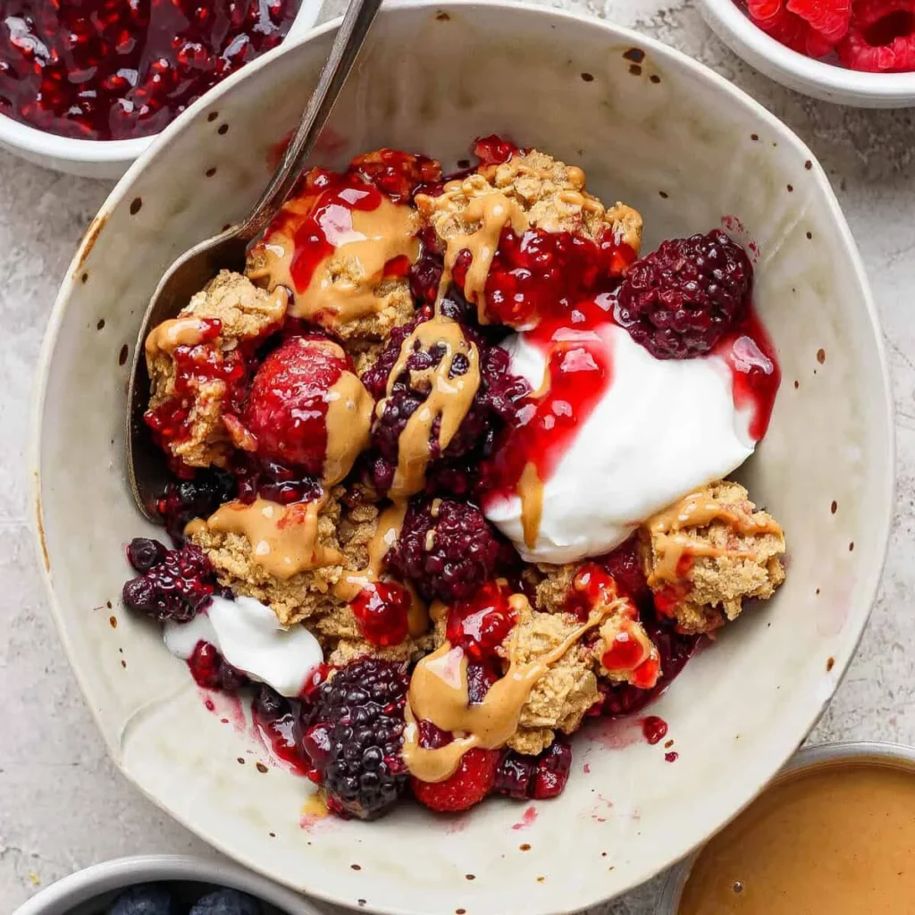 Bowl of PB&J protein berry crumble with peanut butter drizzle