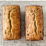 Two golden loaves of sourdough banana bread cooling on a wire rack