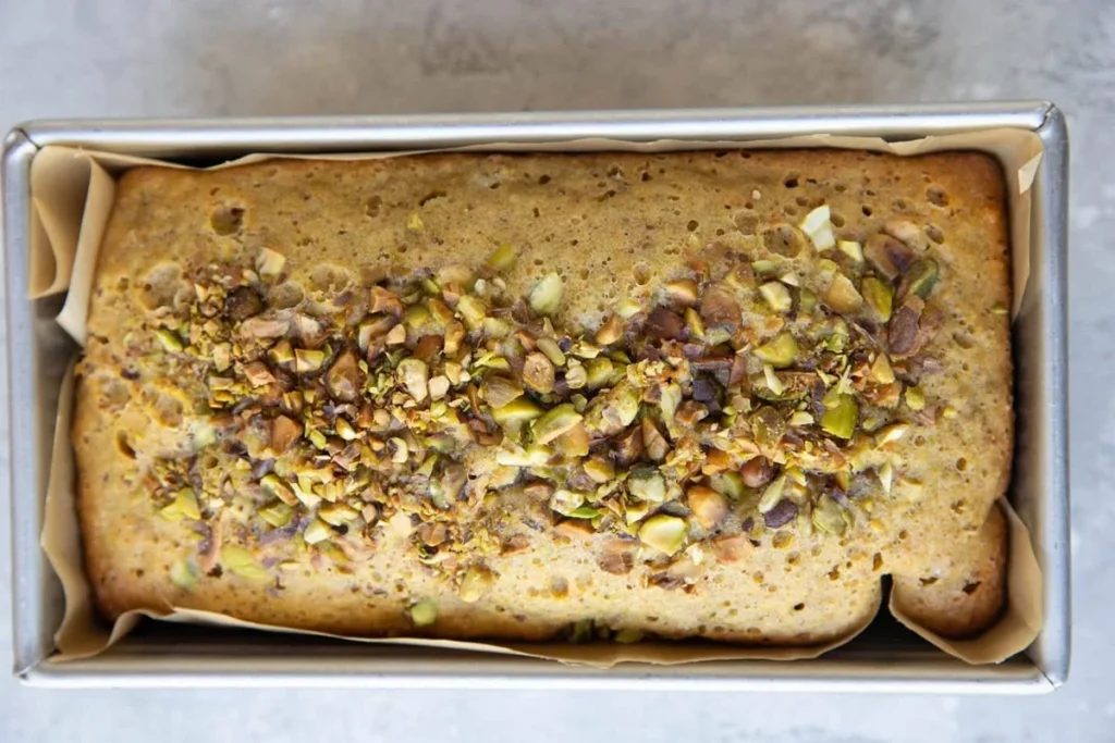 Sliced pistachio cake loaf topped with chopped pistachios