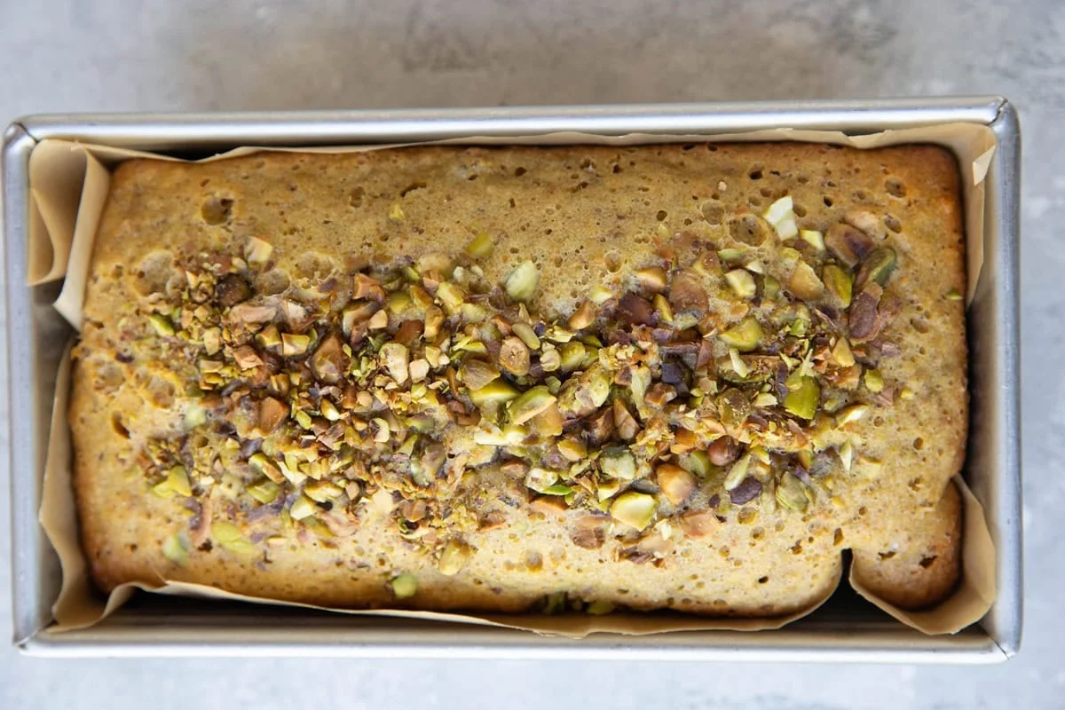 Sliced pistachio cake loaf topped with chopped pistachios