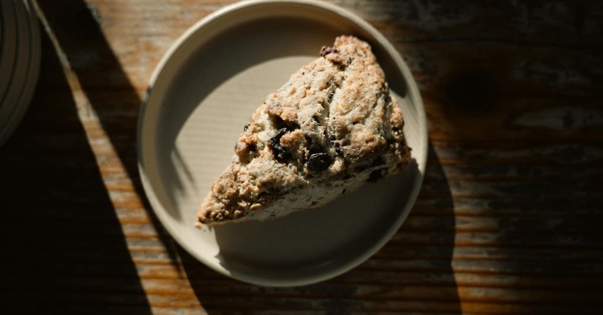 Freshly baked triangular scone with dark chocolate chunks on a plate