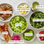 Flat-lay of salad ingredients in labeled bowls on a marble surface