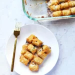 Close-up of crispy tater tots bubbling on top of the casserole