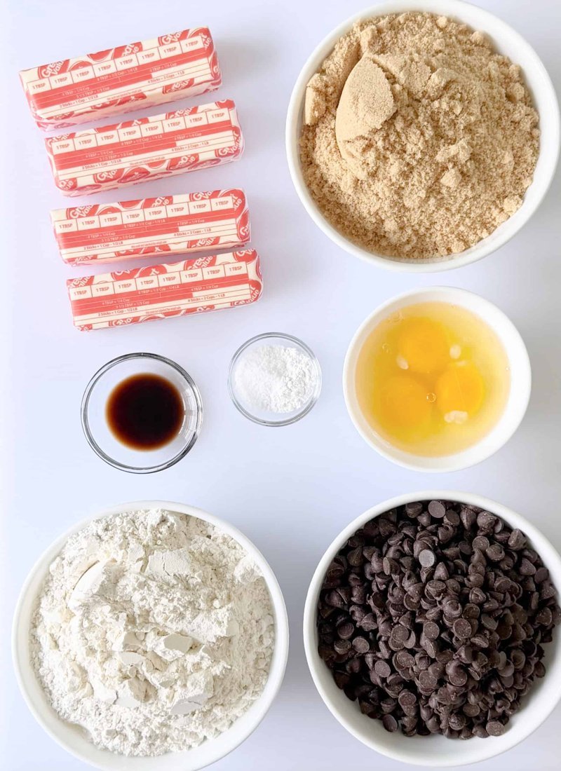 Cookie ingredients laid out: butter, brown sugar, eggs, flour, chips