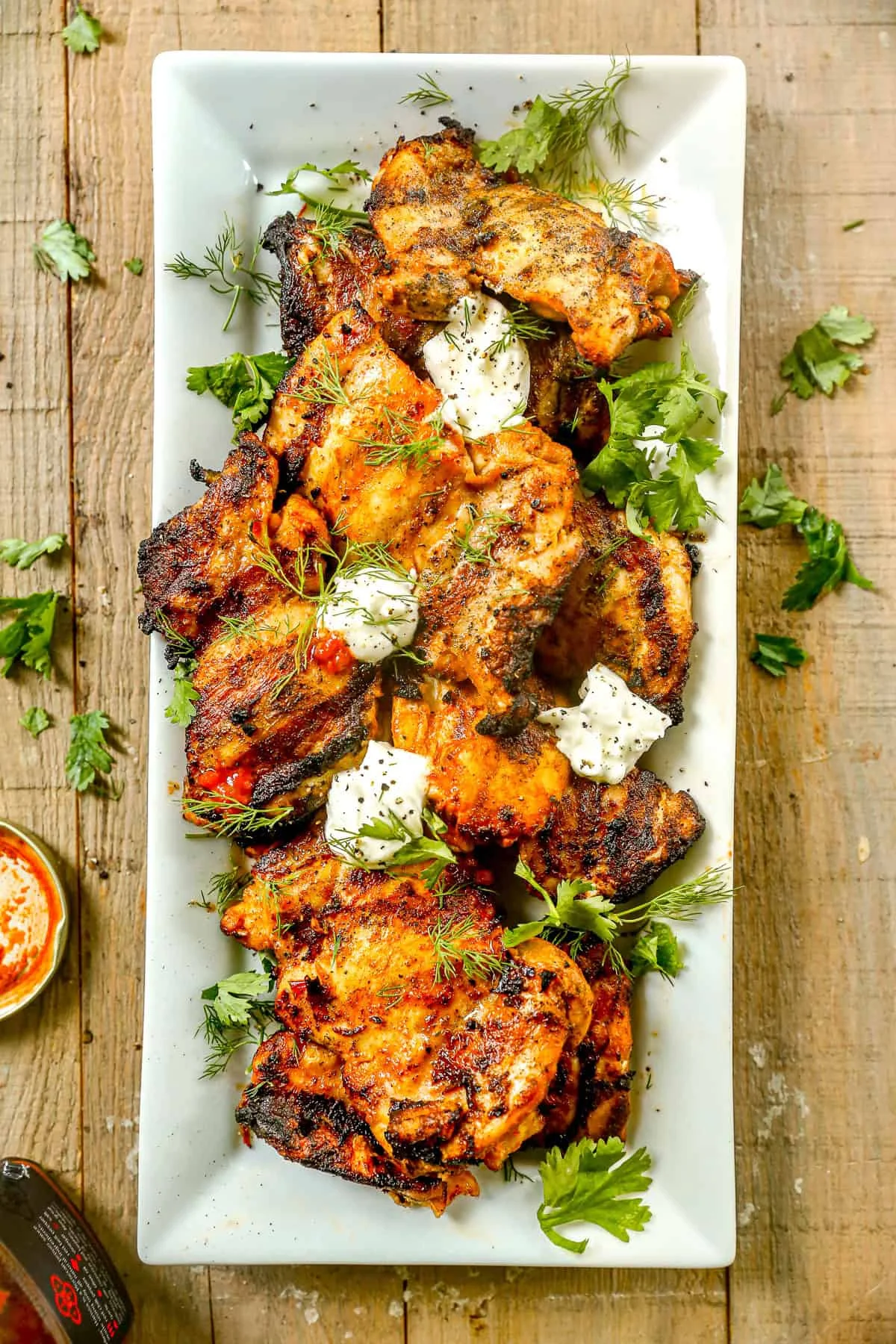 Harissa chicken plated with herbs and a side of yogurt