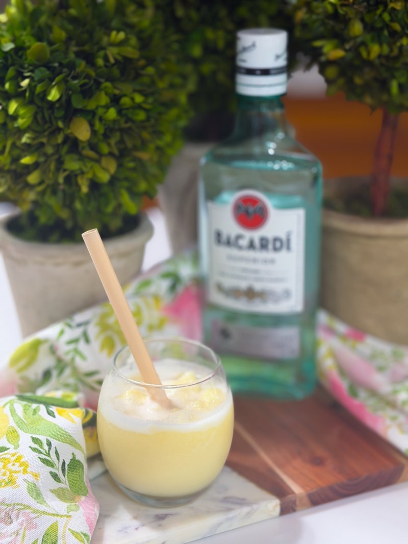 Piña coladas with rum bottle on wooden tray
