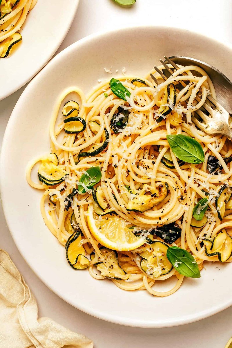 Finished lemy zucchini pasta bowl topped with Parmesan, basil, and red pepper flakes
