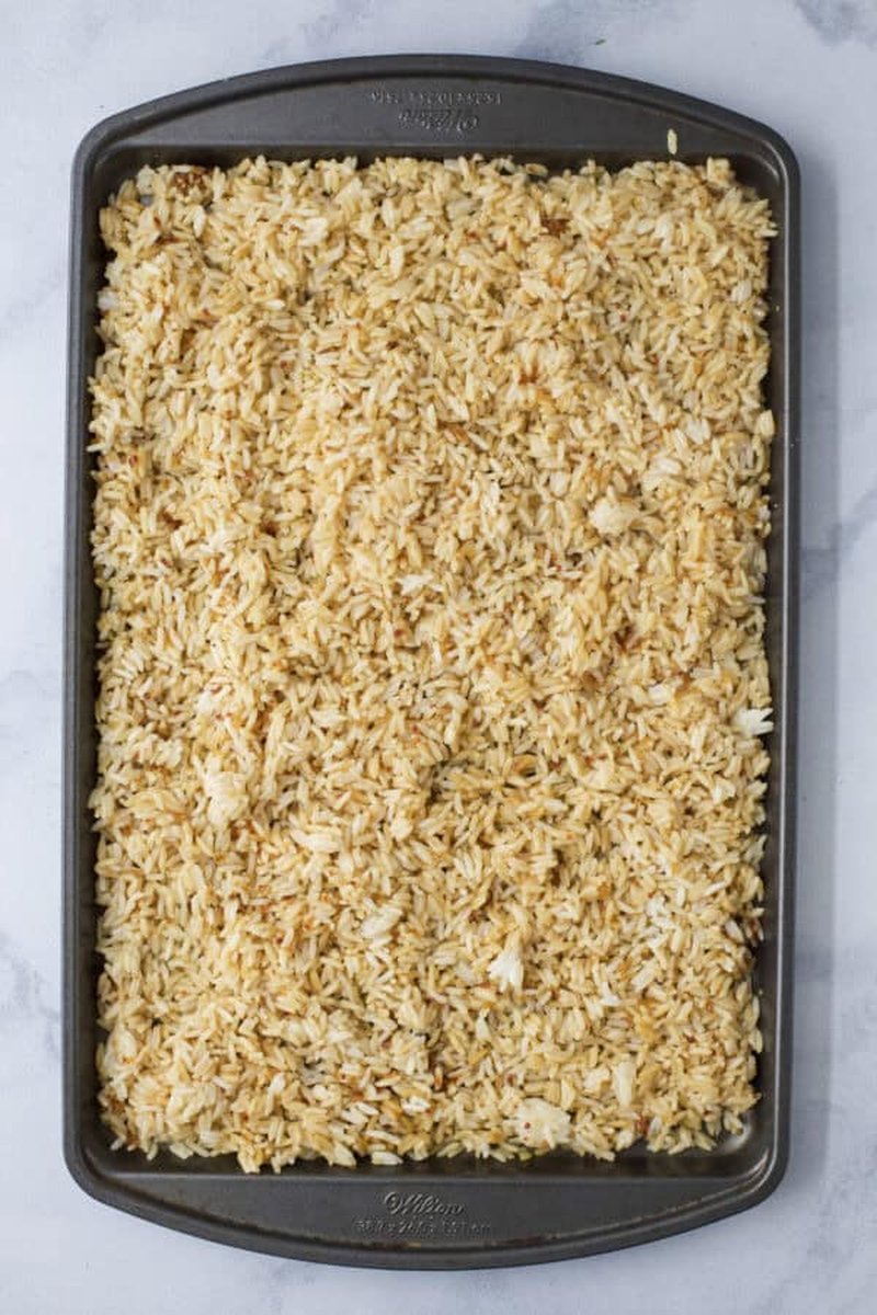 Crispy rice spread in an even layer on a sheet pan