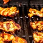 Marinated harissa chicken grilling with visible grill marks
