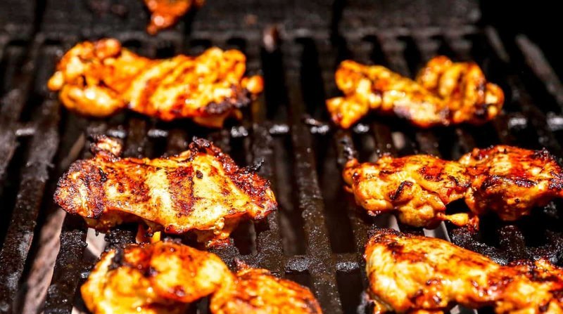 Marinated harissa chicken grilling with visible grill marks