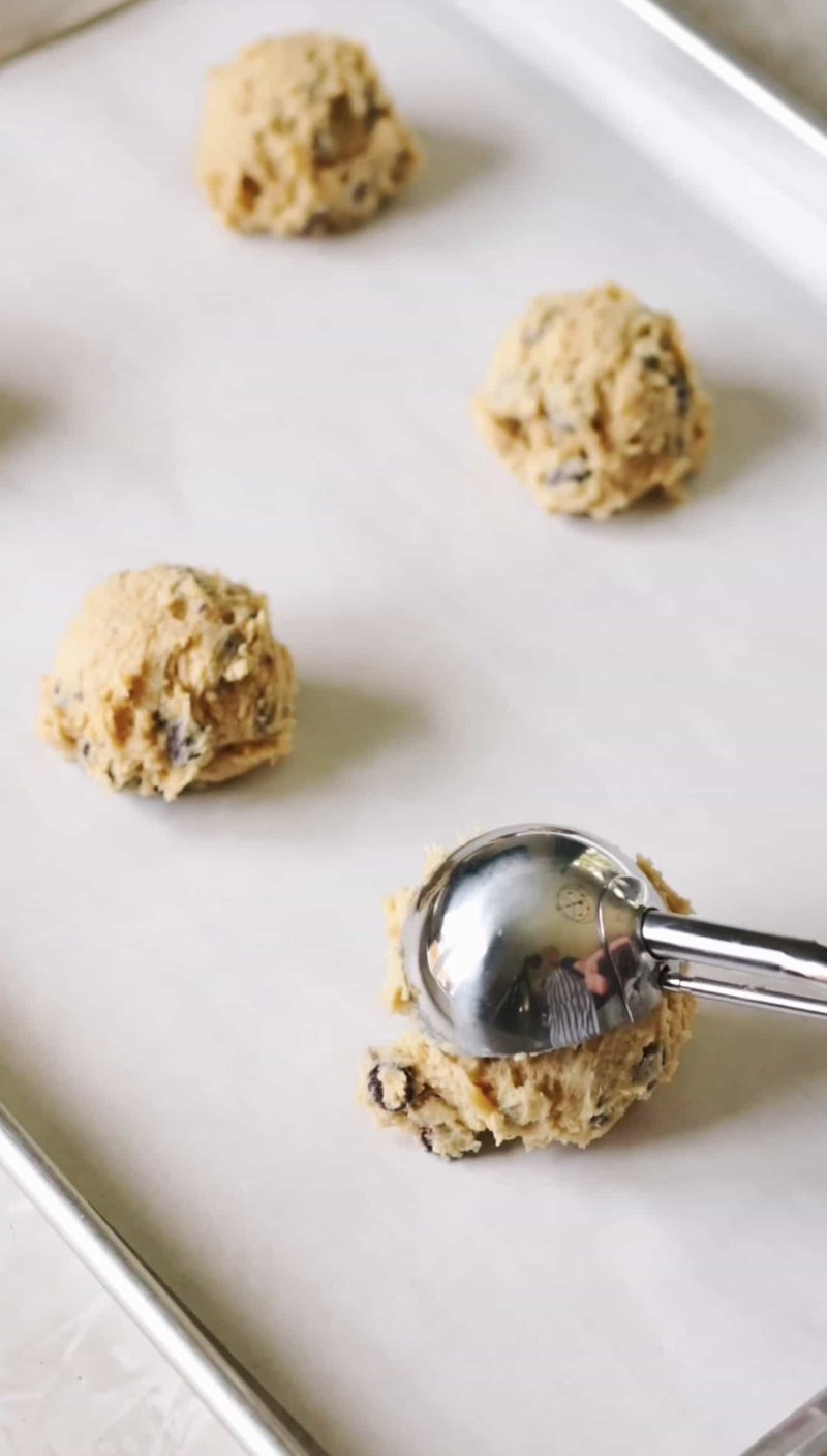 Cookie dough scooped into even balls on a parchment-lined sheet