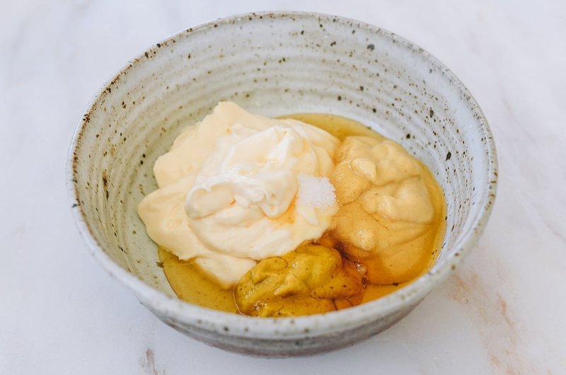 Bowl with mayonnaise, mustard, and honey unmixed, ready to be stirred together