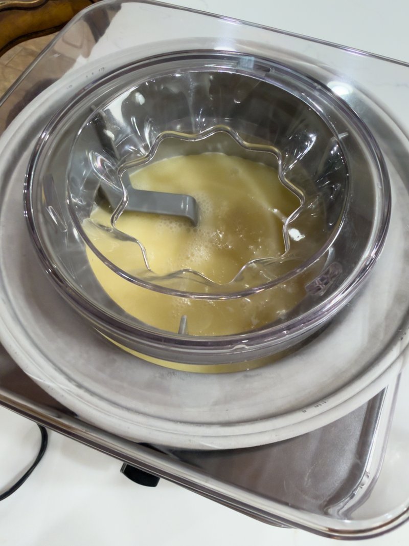Creamy pale yellow frozen base churning in ice cream maker