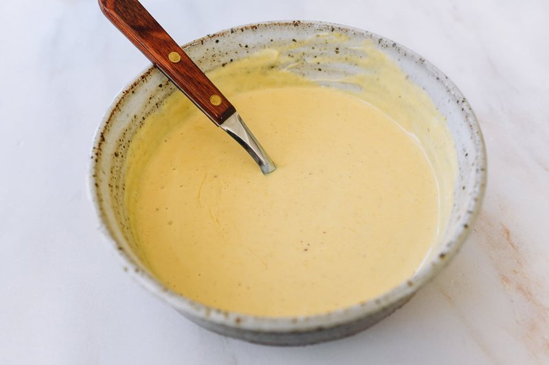 Finished mixed honey mustard sauce in a ceramic bowl with a wooden spatula