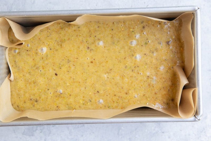 Pistachio cake batter poured into a lined loaf pan