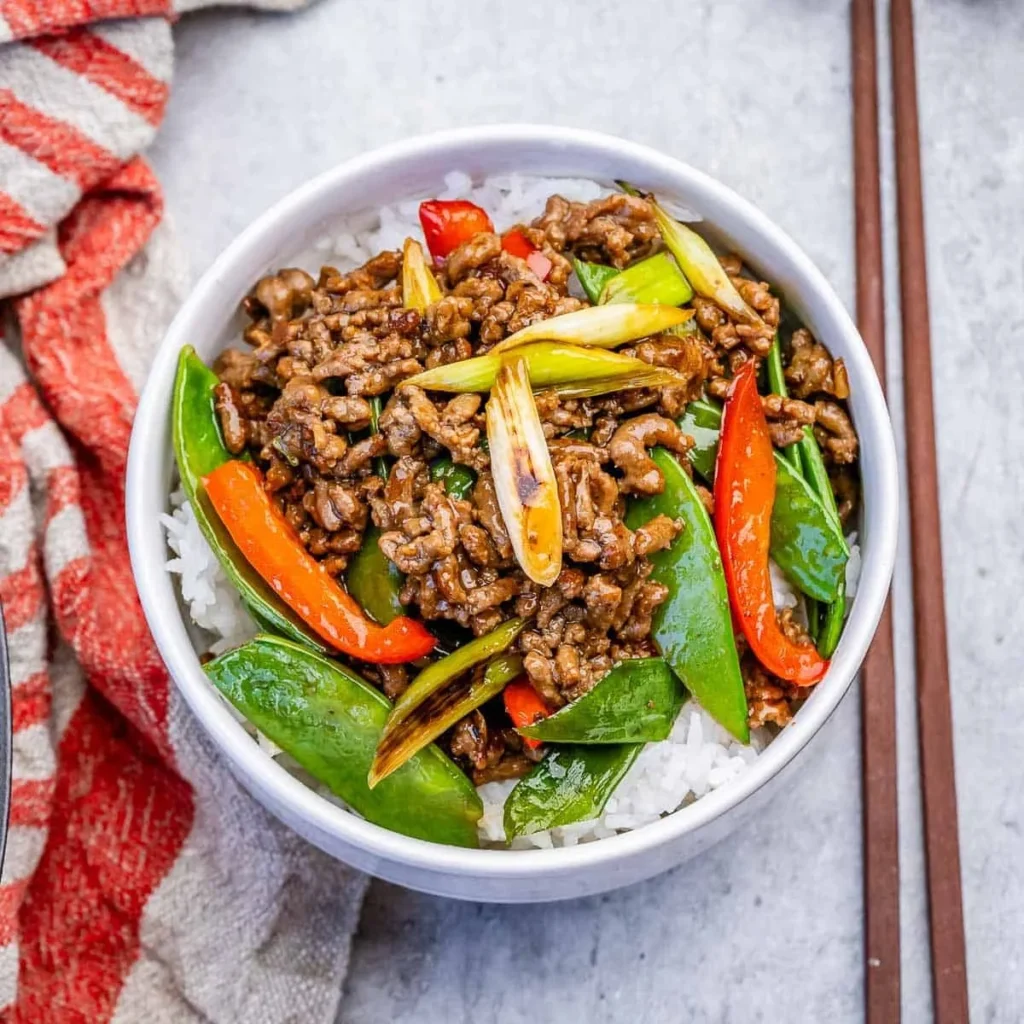 Ground beef stir fry with snow peas and rice in a bowl