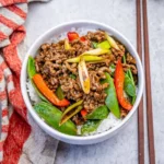 Ground beef stir fry with snow peas and rice in a bowl