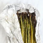 Grilled asparagus spears in an opened foil packet with charred tips