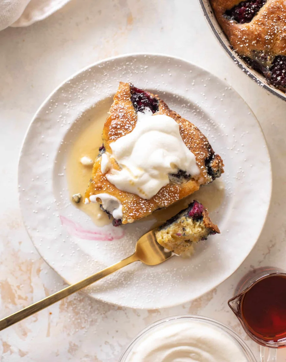 Slice of blackberry pancake topped with whipped cream