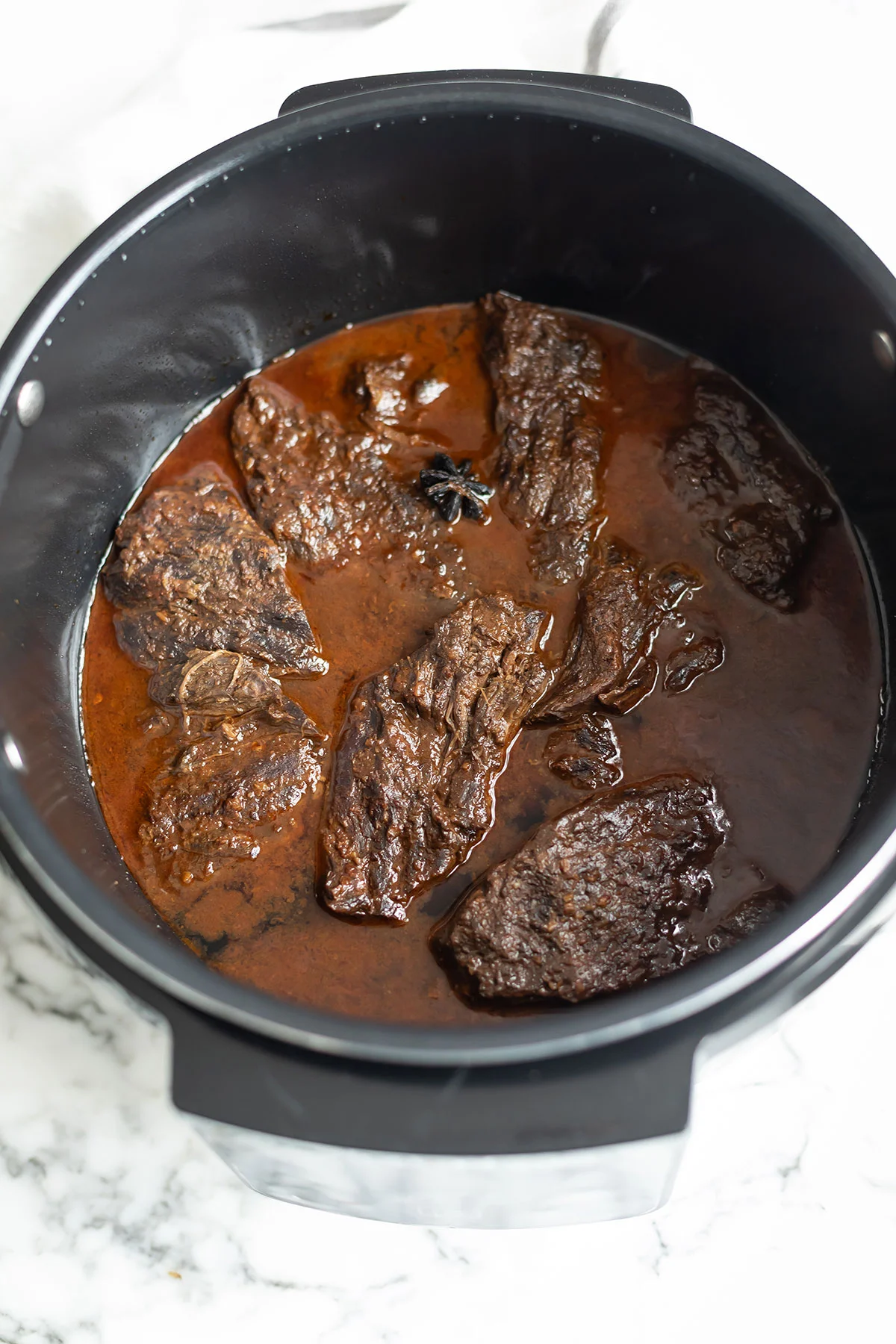 Shredded beef braising in glossy gochujang sauce inside a slow cooker