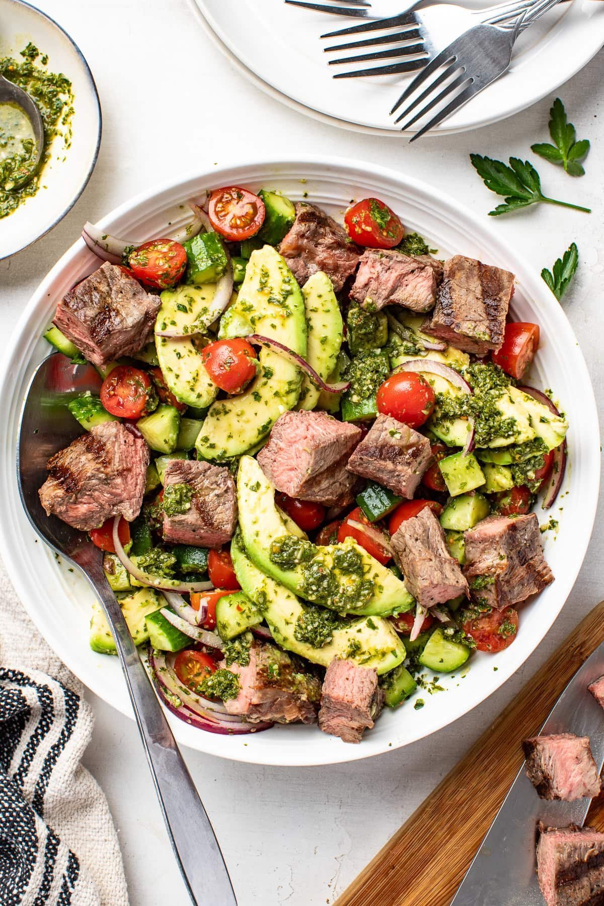 Close-up of chopped steak salad topped with chimichurri