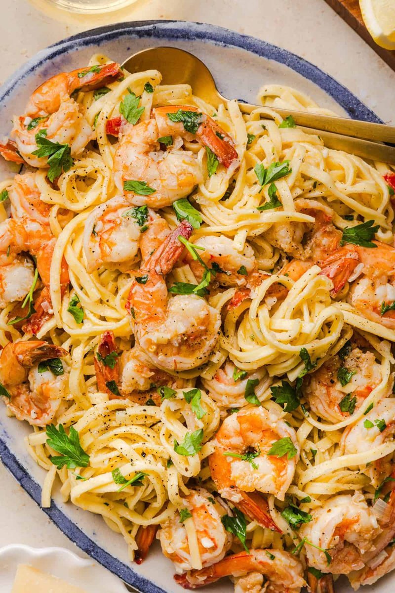 Plated shrimp scampi topped with fresh parsley and lemon wedges
