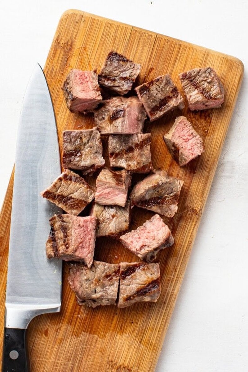 Cubed grilled steak resting on a cutting board